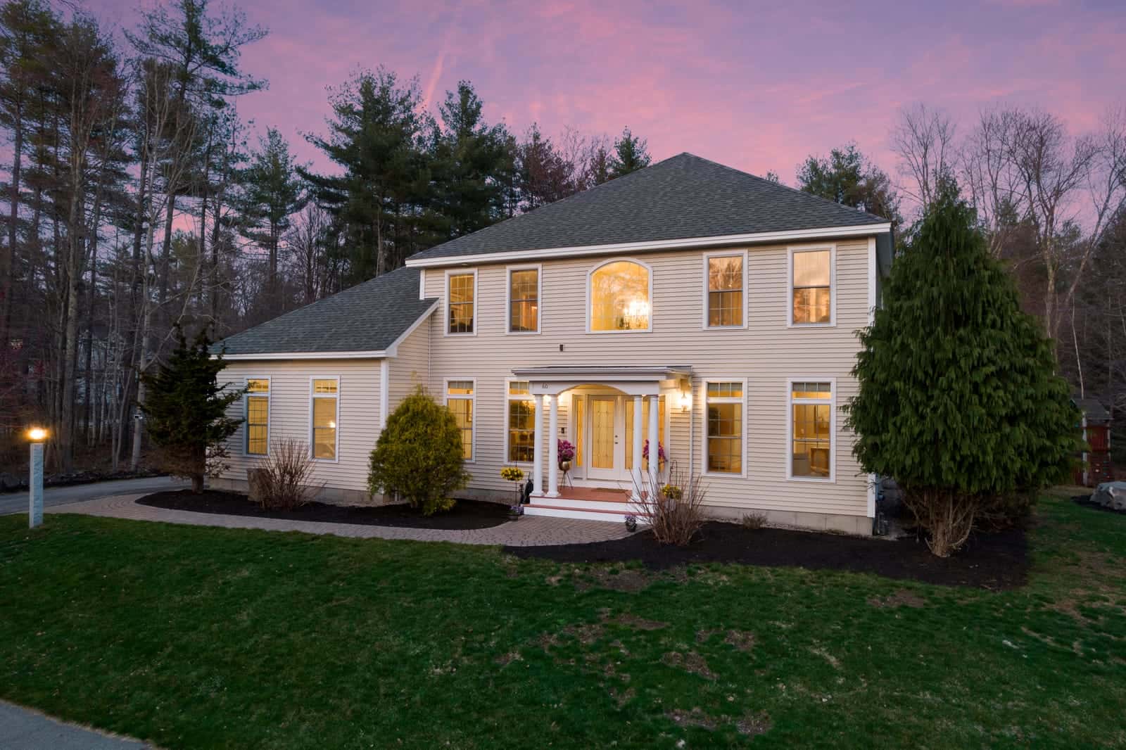 Twilight exterior photo of a home in Dover, New Hampshire, windows glowing at dusk