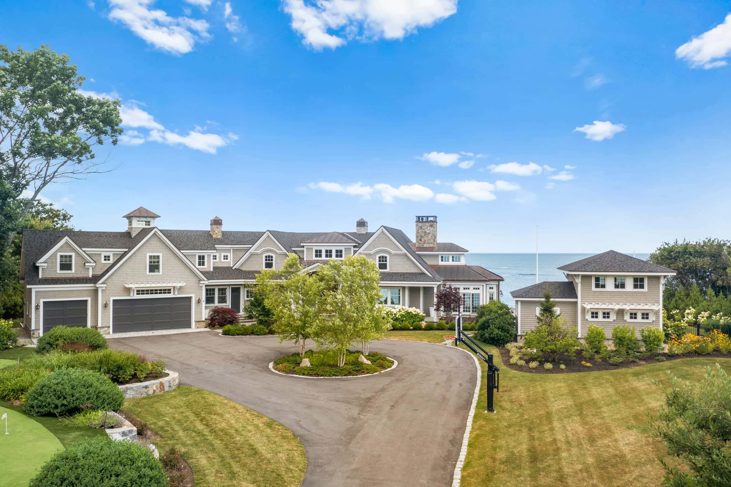 Aerial drone photo of a shingle-style oceanfront estate in York, Maine, with the open Atlantic behind it