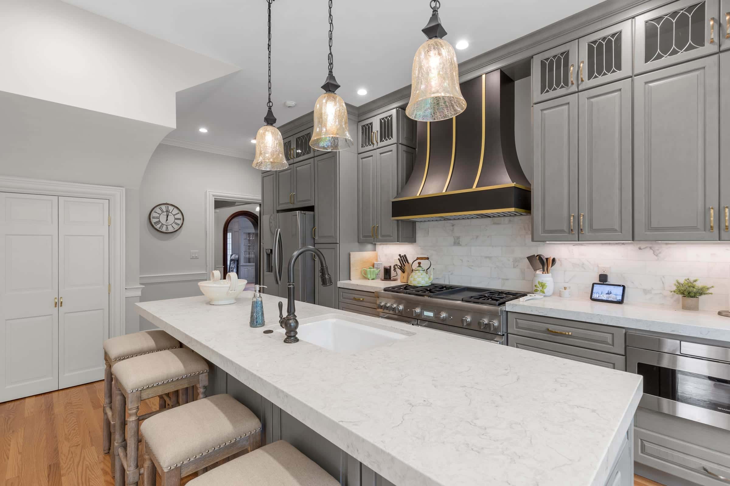 Luxury kitchen interior with marble island and brass-trimmed range hood in Hamilton, Massachusetts